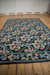 Detailed curvilinear floral vines and blossoms in dusty pink, blue, and green chainstitch.
