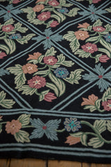 Chainstitch rug detail: scrolling vines, floral motifs in raspberry, celadon, and denim blue.