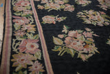 Curvilinear dusty mauve and olive floral sprays on dark vintage chainstitch rug border.
