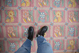 Dusty mauve chainstitch carpet detail with saffron yellow, sky blue floral sprays and vines.