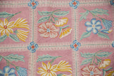 Vivid floral sprays and scrolling vines on pink chainstitch rug, with blue and yellow blossoms.