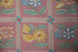 Chainstitch rug detail: dusty mauve curvilinear florals in sky blue, saffron yellow, jade green.
