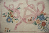 Pink ribbons and multi-colored floral sprays with spiraling chainstitch texture on ivory.