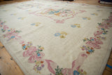 Hand woven India chainstitch carpet detail, showcasing pink bows, blue flowers, and spiraling ivory field.