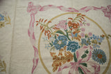 Intricate curvilinear floral bouquet with pink ribbons and subtle spiraling texture.