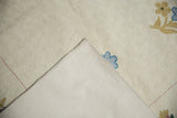 Vintage chainstitch rug corner revealing cotton canvas backing and ivory curvilinear spiraling texture.