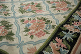Curvilinear chainstitch floral detail on ivory field with pale blue trellis and navy border.