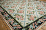 Vintage chainstitch carpet corner, dark floral border contrasting ivory field with blue ribbon trellis.