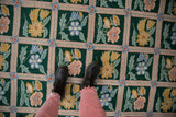 Chainstitch carpet's emerald green field, dusty rose trellis, saffron and blue floral sprays.