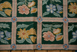 Vintage chainstitch rug's curvilinear blue flower and pink trellis on emerald green.
