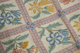 Chainstitch carpet with curvilinear pastel floral sprays and scrolling tendrils in a mauve lattice.
