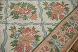 Quaint chainstitch floral sprays and ribbon trellis in rose, ivory, and slate blue, with border.