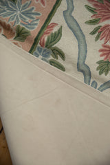 Vintage chainstitch carpet: cream canvas backing and dusty rose, blue curvilinear pattern.