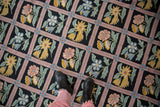 Curvilinear floral sprays within a dusty mauve trellis on a black chainstitch carpet.