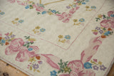 Curvilinear Savonnerie style chainstitch rug corner with pink bows and pastel flowers.