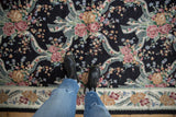 Vintage chainstitch carpet: curvilinear pastel roses, ribbons on black field, floral border.