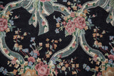 Detailed curvilinear ribbons and floral bouquets in blush, blue, and green on a black chainstitch rug.