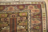 Corner of vintage Melas rug showcasing rust, olive, and beige finned plant border motifs.