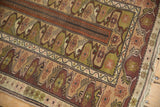 Vintage Melas rug detail: hand-knotted geometric border, rust, olive green, and beige stylized motifs.