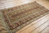 Stylized geometric border pattern on a vintage Melas rug, showing rust, olive, and ivory.