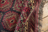 Rolled edge of Afghani Daulatabad rug, showing fuchsia guls, ram's horn outlines, and fringes.