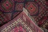 Corner of vintage Daulatabad rug, revealing fuchsia guls, intact fringe, and a floral border.