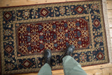 A personal view showing the in-room scale of a vintage Armenian rug with a burgundy and deep teal pattern.