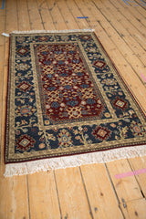 Angled perspective of the vintage Armenian rug with its burgundy Herati-design field and wide palmette border.