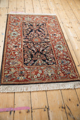 Angled view of an Armenian Hamadan rug displaying its plush pile and floral chestnut border.
