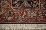 A vintage Armenian rug's scrolling floral border in navy and chestnut with its ivory fringe.