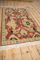 Angled view of the vintage Armenian Sultanabad rug's plush terracotta pile and ivory fringe.
