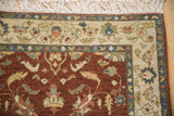 Corner of a vintage Armenian rug with a dense wool pile, floral ivory border, and neat white fringe.