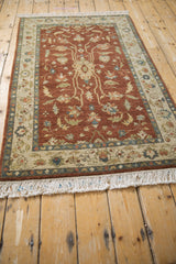 Angled view of the vintage Armenian rug, showing the copper field, floral palmette, and clean ivory fringe.