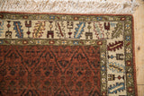 Corner of a vintage Armenian rug showing the serrated leaf border and full ivory fringe.