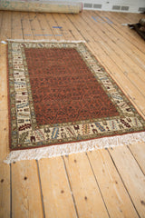Angled perspective of a vintage Armenian rug with a rust trellis field and detailed ivory border.
