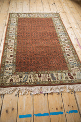 Low angle view of a vintage Armenian rug showing its rust trellis field and detailed border.