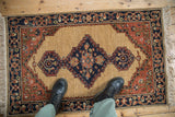 A vintage Armenian rug with a serrated diamond medallion and navy blue meandering vine border.