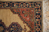 Detail of the vintage rug's full wool pile, navy blue meandering vine border, and original ivory fringe.