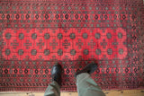 A view looking down at the repeating guls and geometric borders of a vintage raspberry Daulatabad rug.