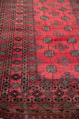 Angled view of the intricate geometric borders and plush raspberry wool pile.