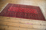 Angled view of a vintage Daulatabad rug showing its repeating geometric guls in raspberry and charcoal.