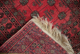 A vintage Daulatabad rug's corner shows the raspberry pile, geometric back weave, and ivory fringe.