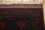 Close-up of vintage Pakistani Turkmen rug fringe and cherry red serrated diamond motifs.