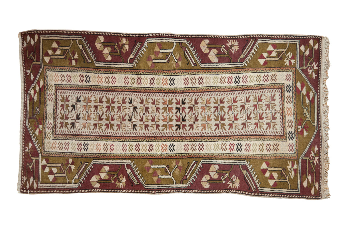 Vintage Melas rug with geometric floral arrangements in moss green, pale plum, and silver tones.