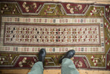 Overhead view of a vintage Melas rug showing the scale of its geometric pattern on the floor.