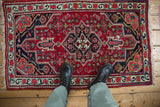 Scale view of a vintage Bijar rug showing its ruby red field and geometric sapphire blue medallion.
