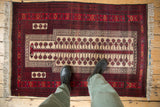 Vintage Belouch design rug corner with ivory snowflake motifs and multi-tiered red borders.