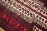 Close-up of Belouch rug: ivory field with cherry red snowflake leaves, geometric borders.