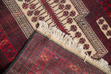 Belouch rug corner showing off-white fringe, charcoal selvage, and red snowflake pattern.