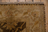 Corner detail of the Oushak carpet's hand-knotted plush pile and secured beige fringe.